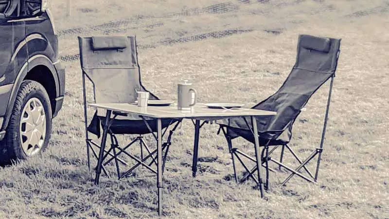 Ein Campingtisch und zwei Stühle auf einer Wiese