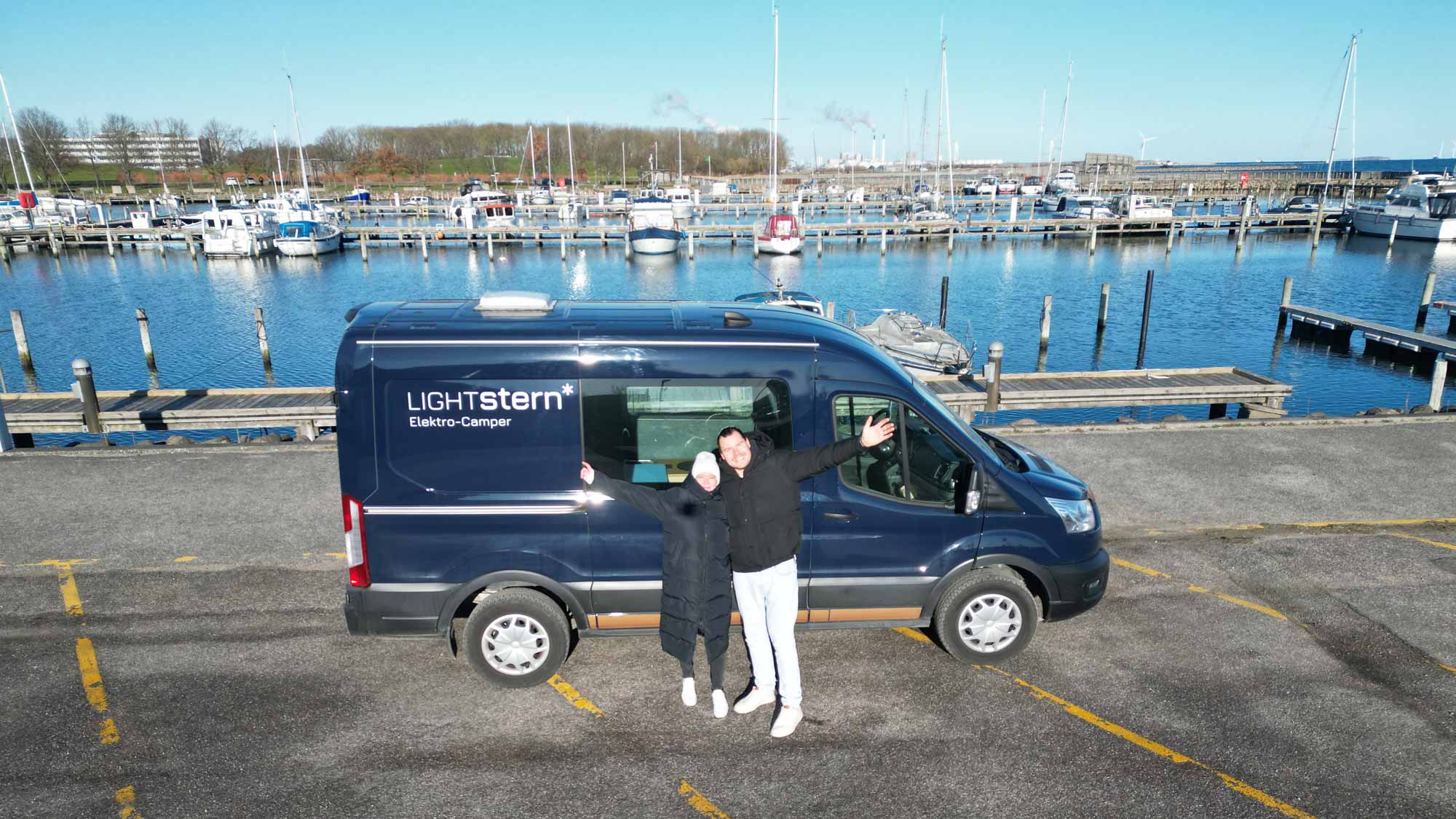 Blogpost-TPOJ Drone-Shot mit dem Polaris im Hafen, Tanja und Björn stehen davor und winken